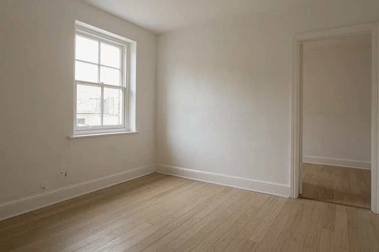 Empty room with a clean oak floor, painted skirting and a sash window